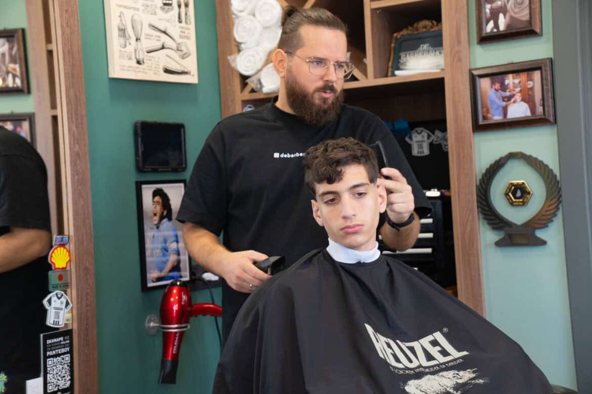Άνδρας barber εκπαιδεύει νεαρό πελάτη σε κομμωτήριο στη Λάρισα.